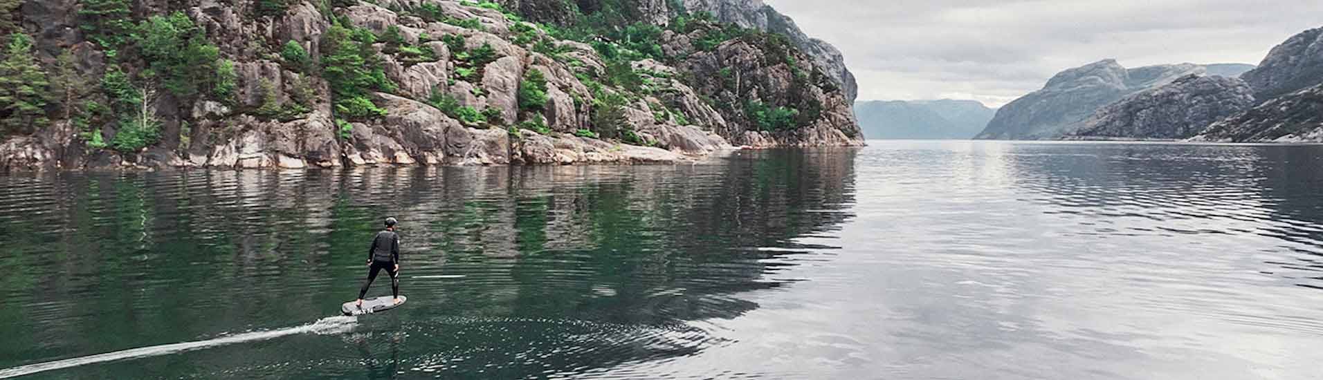 Surfen auf E-Surfboard vor Gebirge
