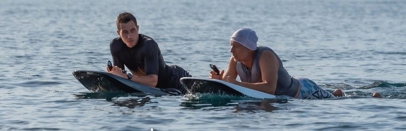 Zwei Männer liegen auf E-Surfboards